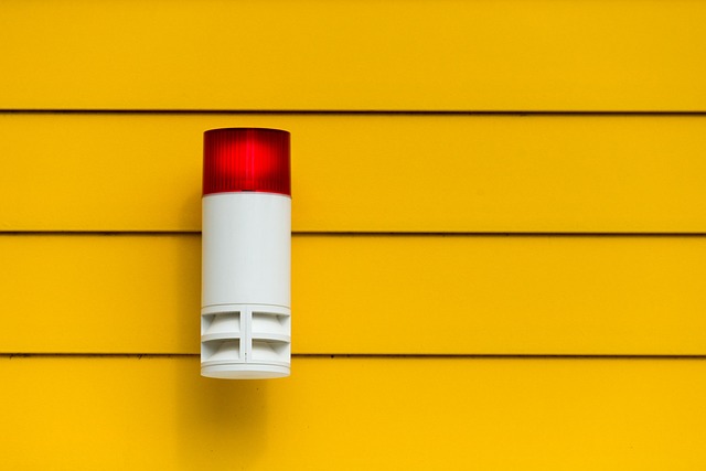 Why Coventry Businesses Need Advanced Intruder Alarm: A white and red alarm siren is mounted on a yellow wall, a common component of business security systems in Coventry.