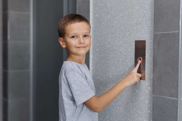 A young boy pressing an elevator button. This highlights the simple interaction of an access control system, an important feature in Access Control Installation for coventry Homes.
