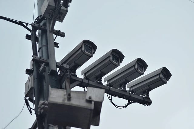 Multiple security cameras mounted on a pole for wide-area surveillance in a commercial setting.