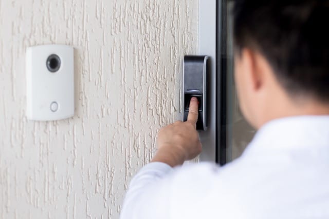 A man using his finger on a biometric access control system to unlock a door. This demonstrates the benefits of Access Control Installation for coventry Homes for added security.