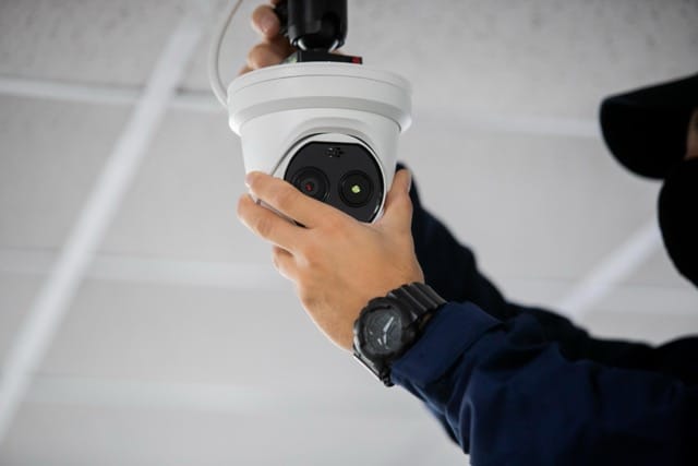 Technician installing a CCTV camera on the ceiling, following essential steps in 'How to Choose the Commercial CCTV Installers' to ensure optimal surveillance for businesses.