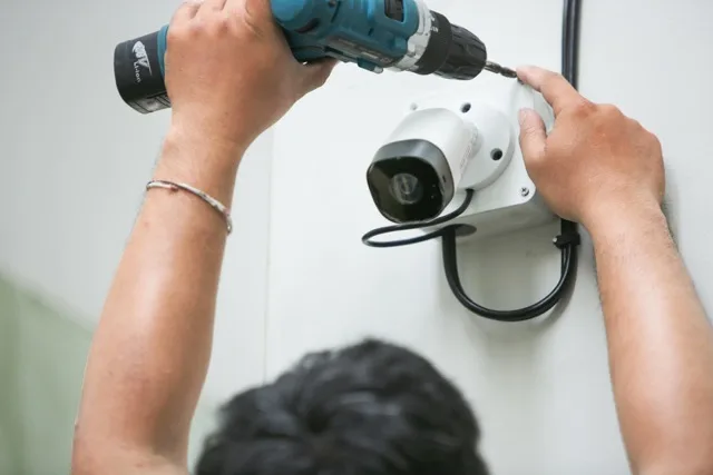 Technician installing a CCTV security camera on the wall, following key steps in 'How to Choose the Commercial CCTV Installers' for business security.