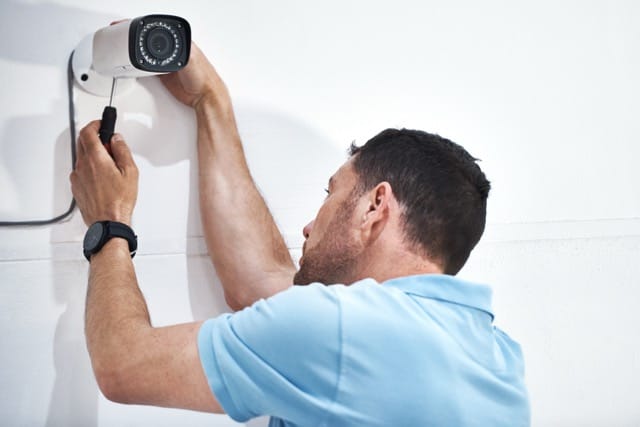 Technician installing a CCTV camera on the wall, demonstrating key steps in 'How to Choose the Commercial CCTV Installers' for optimal security setup.
