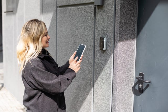 A woman unlocking a door with her smartphone through an access control system. This highlights the convenience of modern Access Control Installation for coventry Homes.