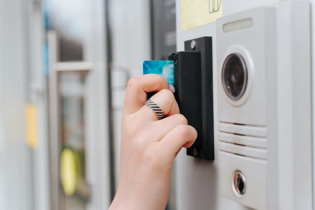 A person uses an access card to enter a building with a modern security system. Discover how to choose the right access control system for your workplace.